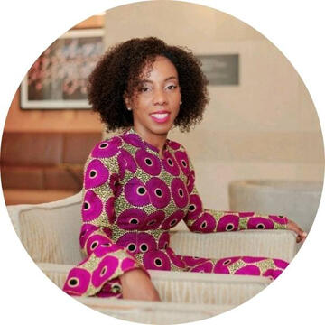 image of black woman wearing a pink patterned dress, smiling at the camera