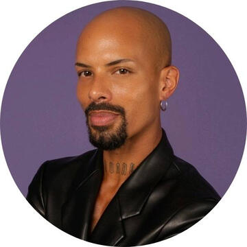 image of black man with a small black goatee, leather jacket, looking at the camera